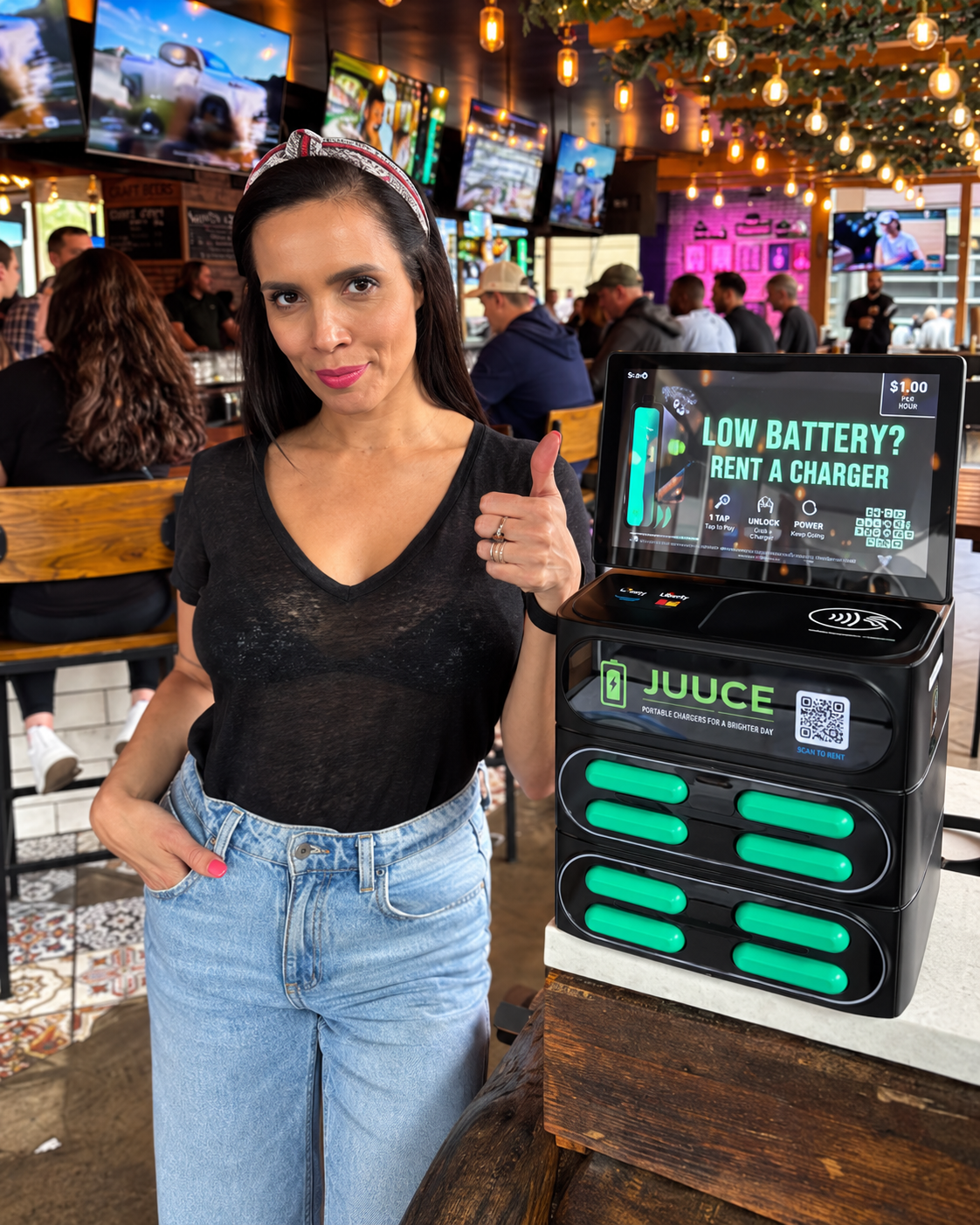 Guest standing beside a JUUCE charging station inside a busy venue